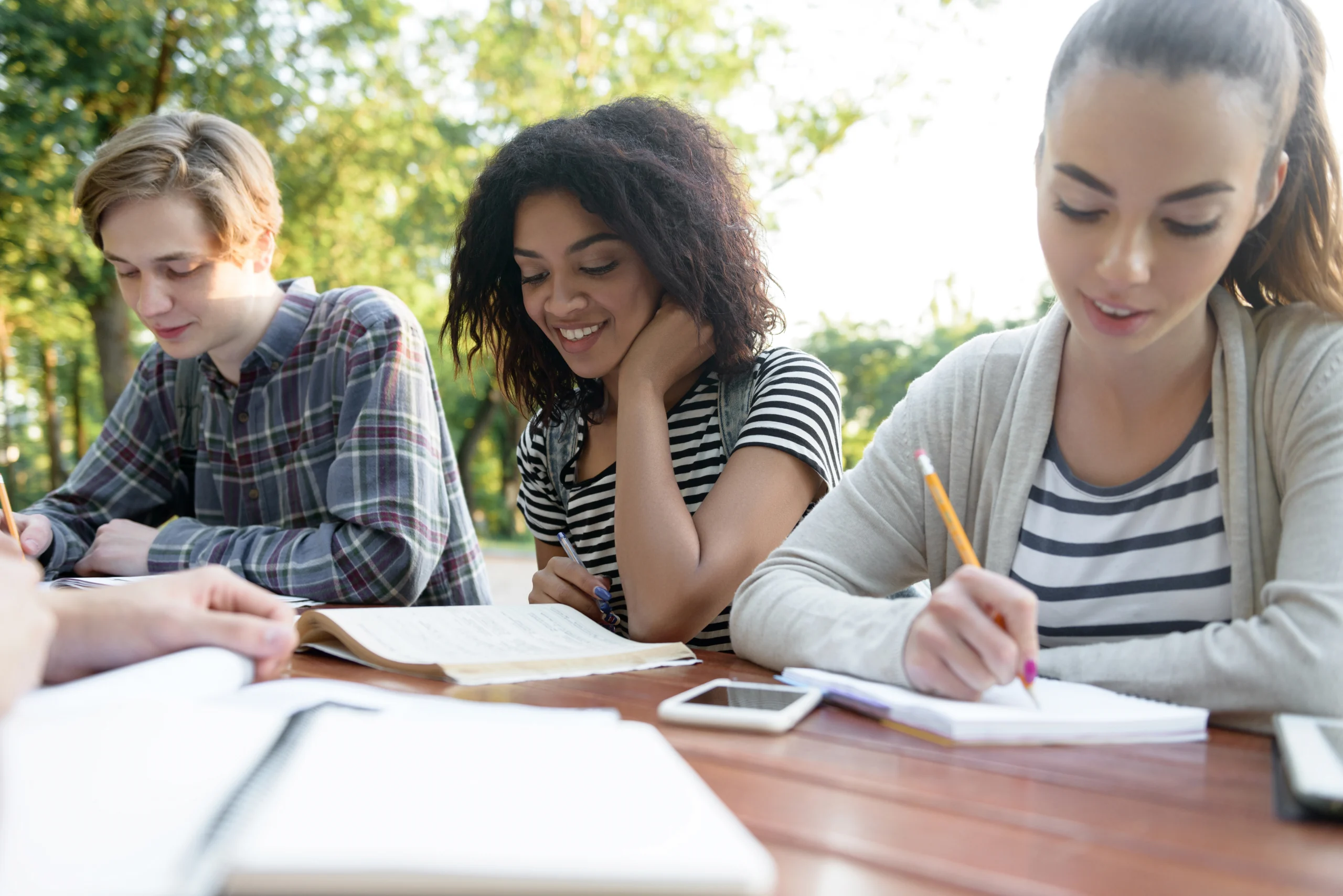 happy_young_people_friends_sitting_studying_outdoors_1.webp